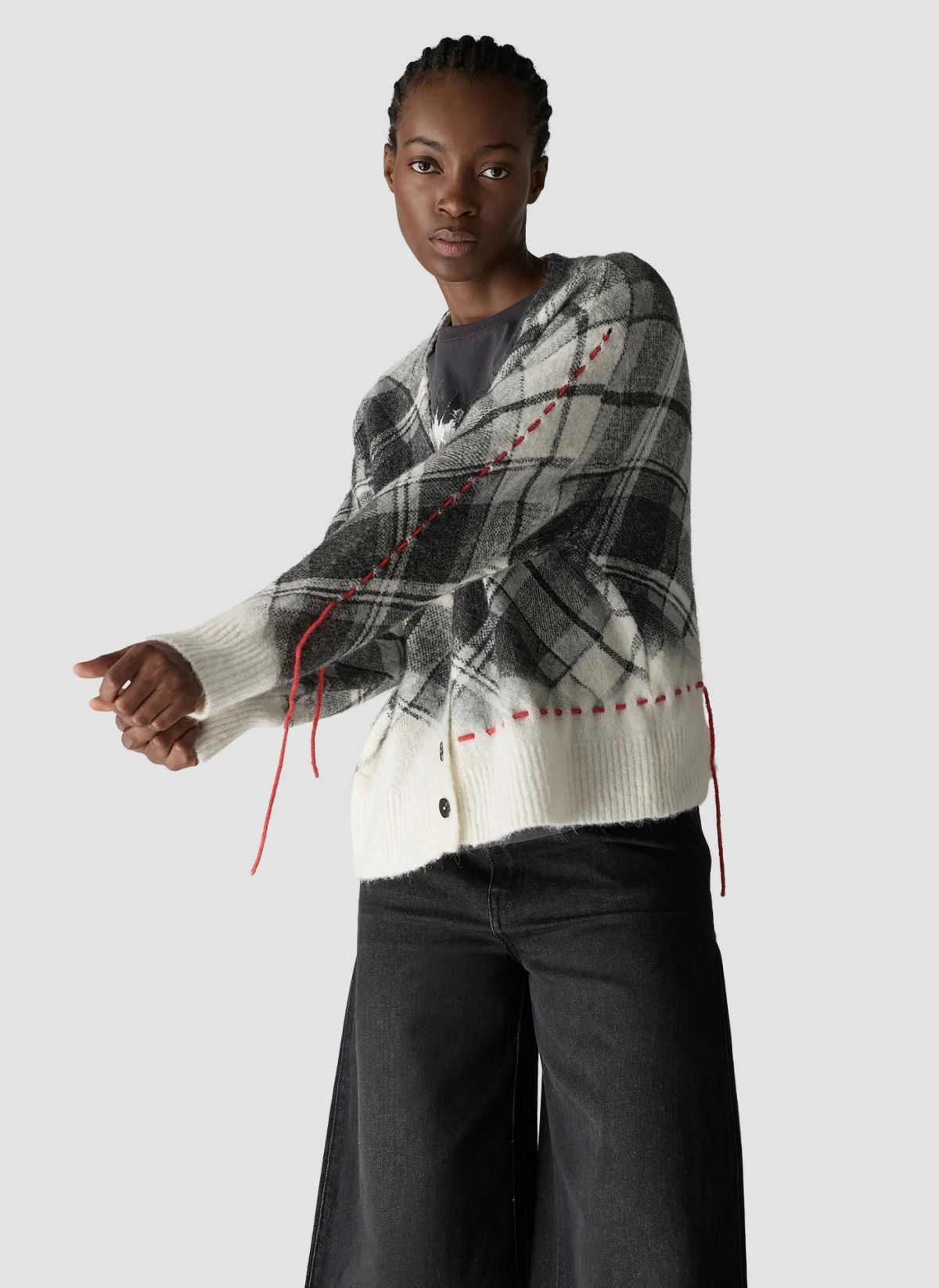 Modelo con cárdigan de cuadros blanco, gris y negro de la colección Otoño Invierno 2026